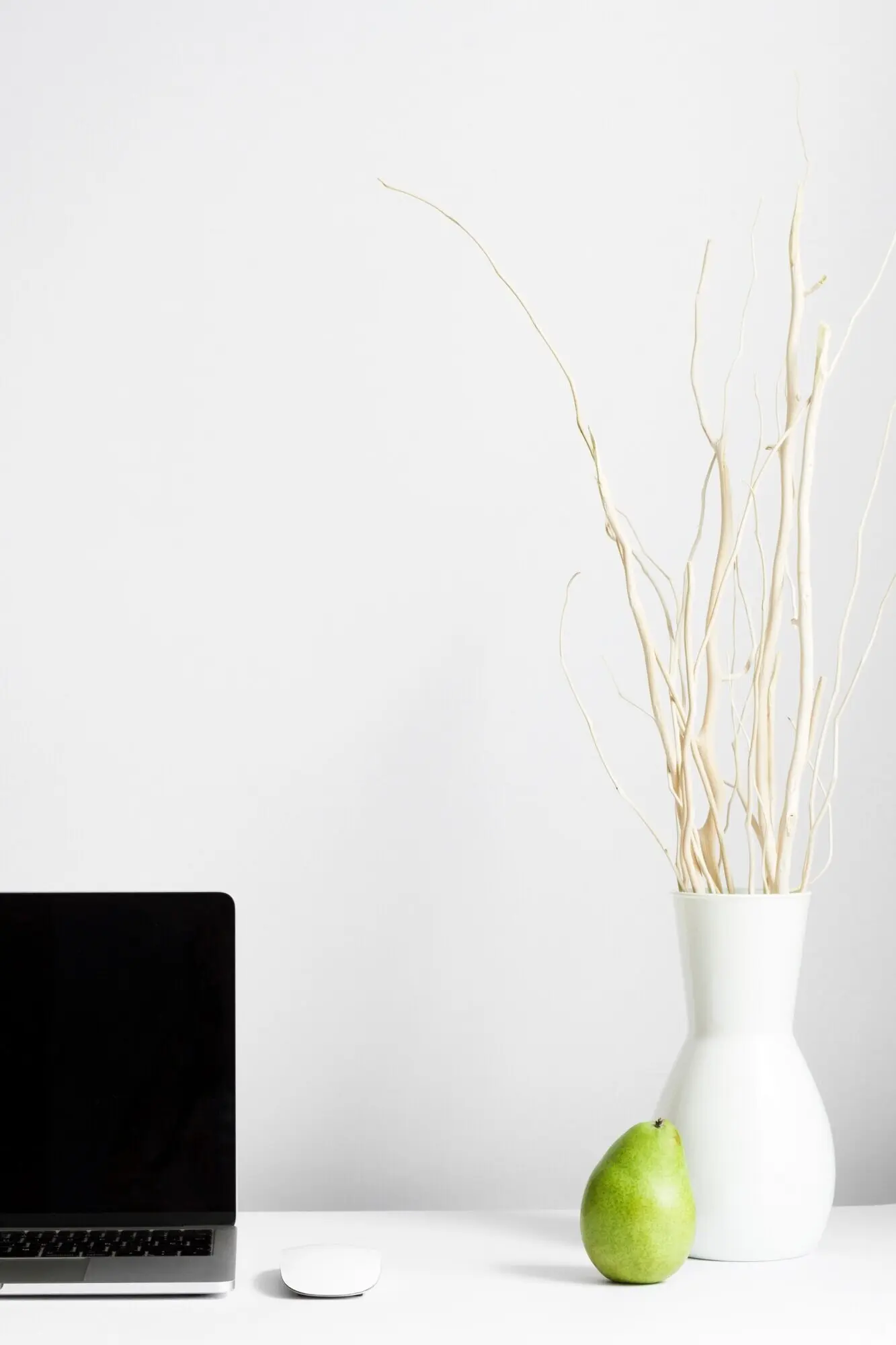 Komposition eines Arbeitsplatzes mit Vase und Laptop auf dem Schreibtisch